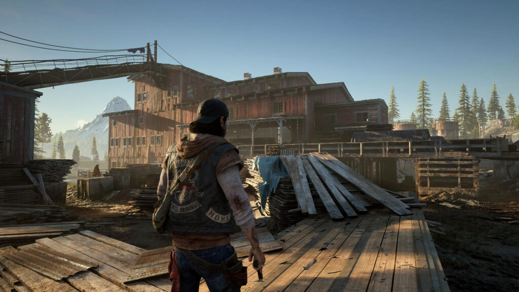 Deacon St John in rugged post-apocalyptic settlement with wooden structures and mountain peaks Wallpaper