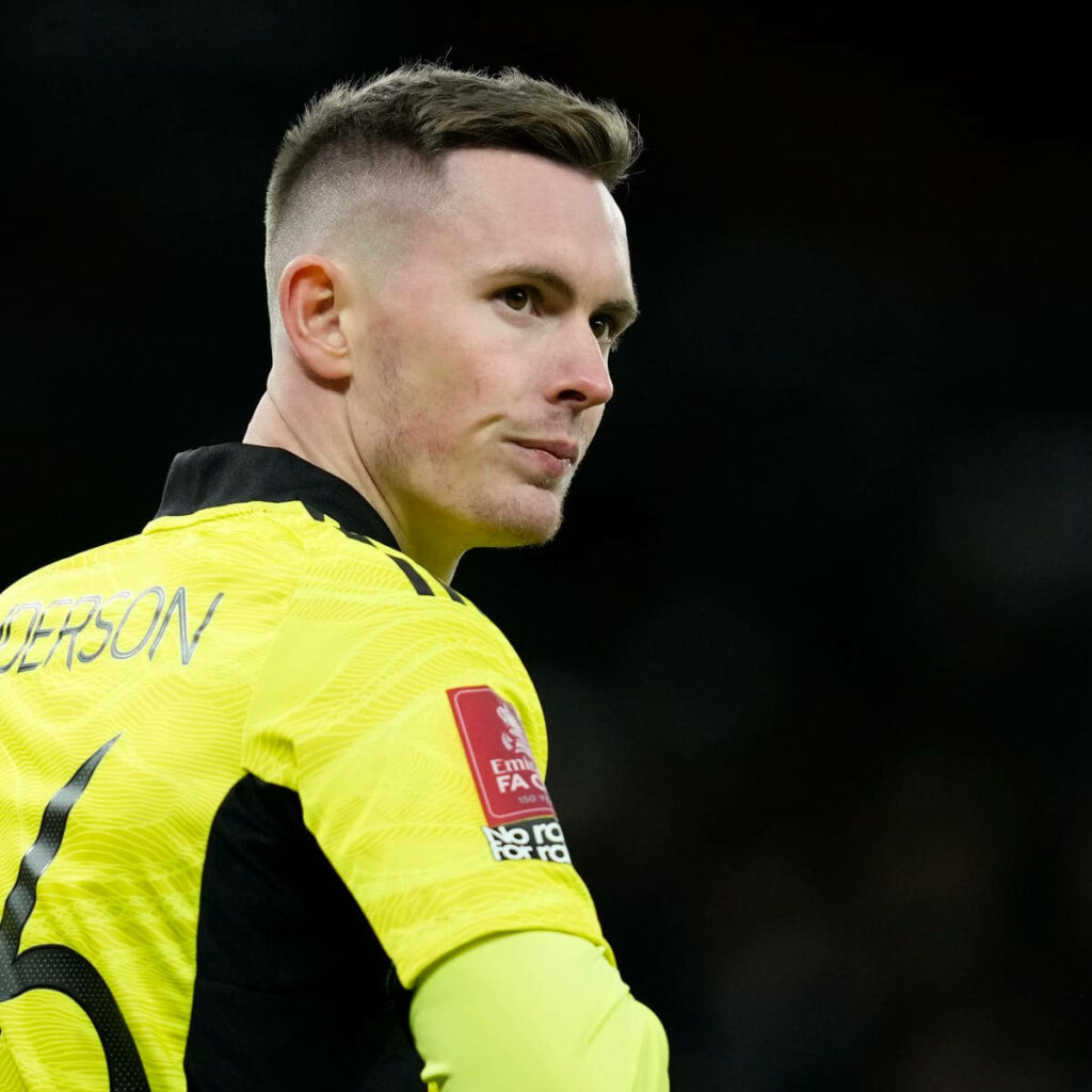 Dean Henderson in yellow goalkeeper jersey smiling confidently with blurred stadium background wallpaper