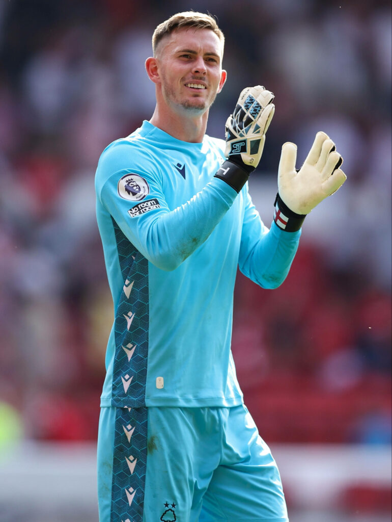 Dean Henderson clapping in light blue goalkeeper kit with vibrant stadium background wallpaper