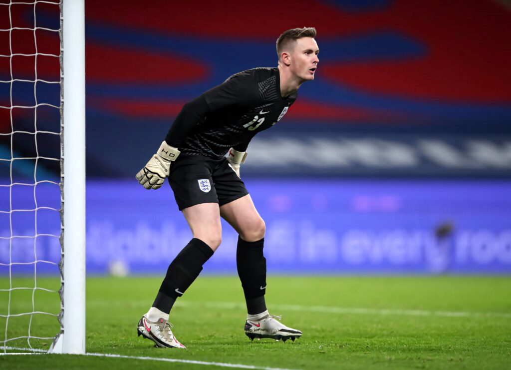Dean Henderson focused goalkeeper in dark kit ready to defend goal under stadium lights wallpaper