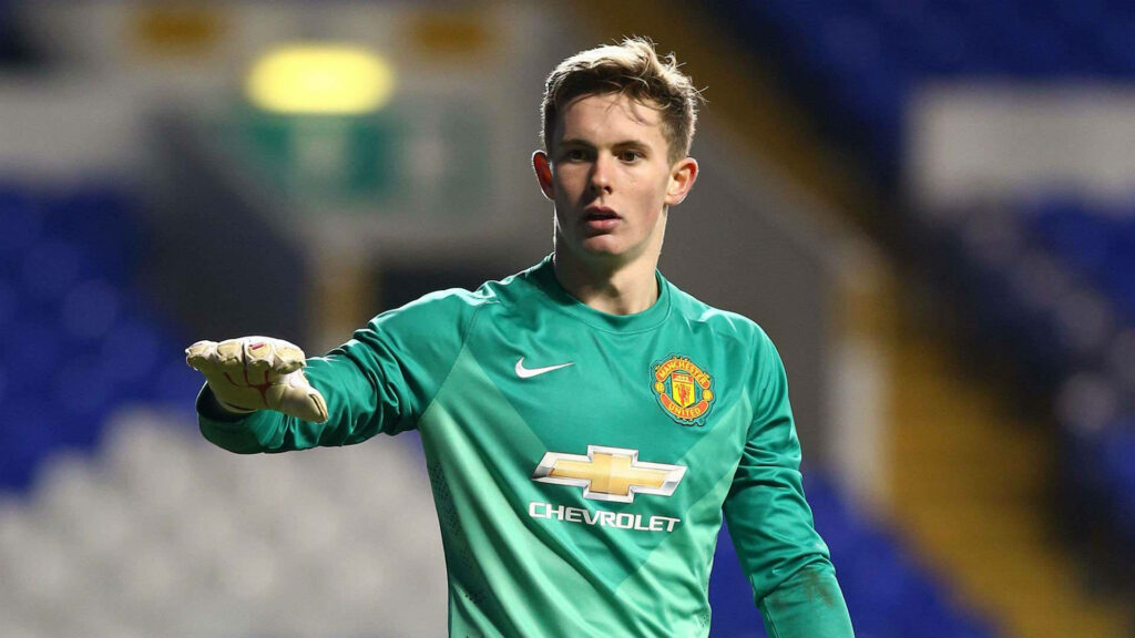 Dean Henderson in green Manchester United goalkeeper kit reaching out during intense match action Wallpaper