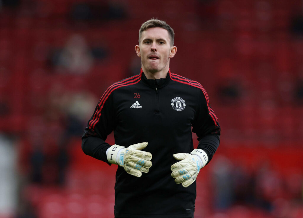 Dean Henderson Manchester United goalkeeper in training kit on field with red stadium seats background Wallpaper