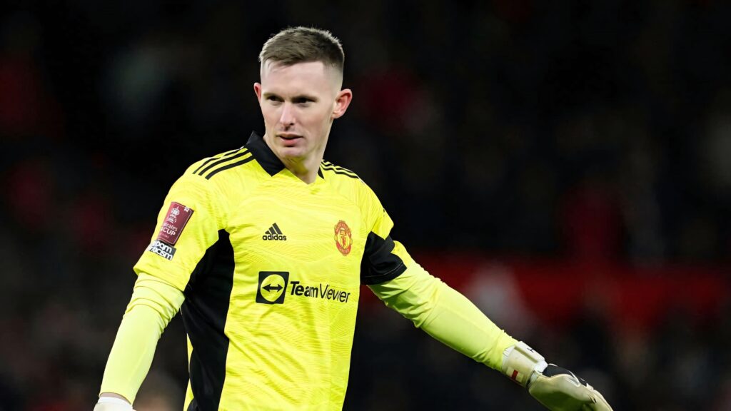 Dean Henderson in bright yellow Manchester United goalkeeper kit ready in dark stadium background Wallpaper
