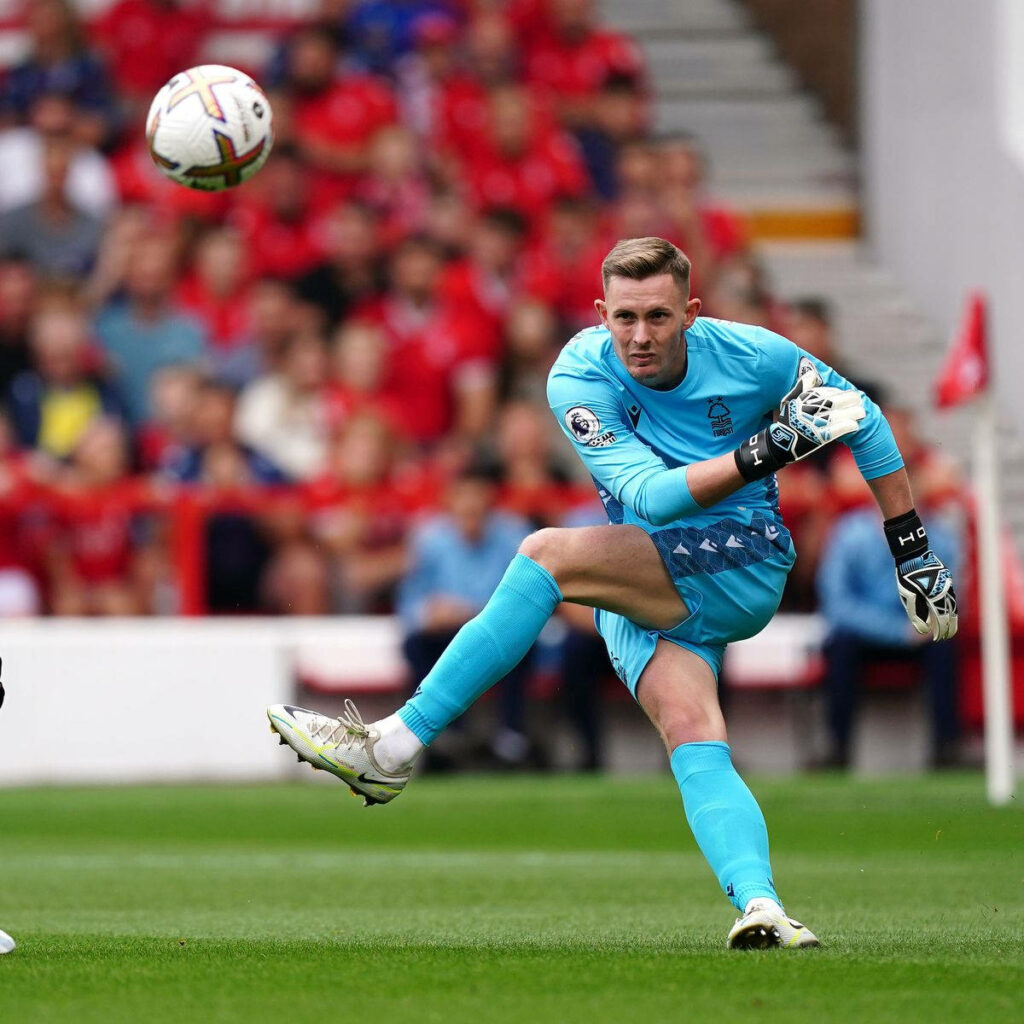Dean Henderson in bright blue goalkeeper kit performing dynamic side kick during football match action Wallpaper