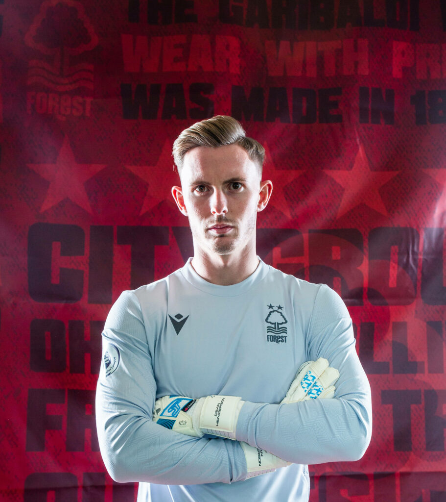 Dean Henderson Nottingham Forest goalkeeper kit red background confident pose sports wallpaper