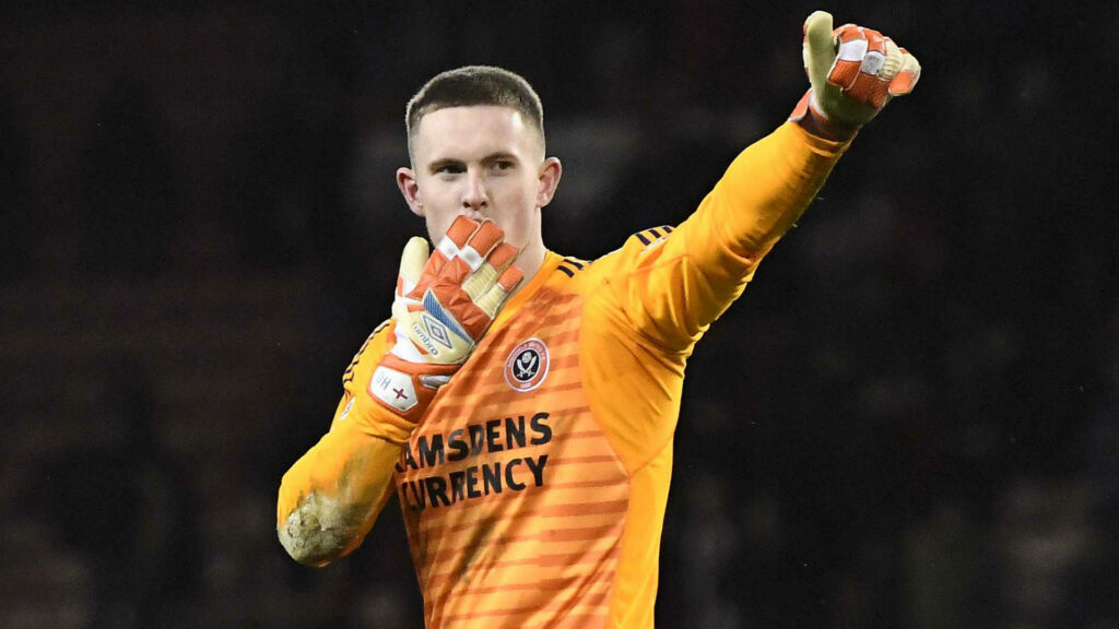 Dean Henderson in orange Sheffield United kit celebrating with fly kiss and raised arm on field Wallpaper
