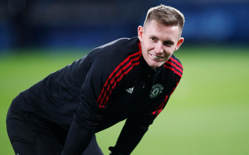 Dean Henderson smiling in black Manchester United training jacket vibrant sports wallpaper background