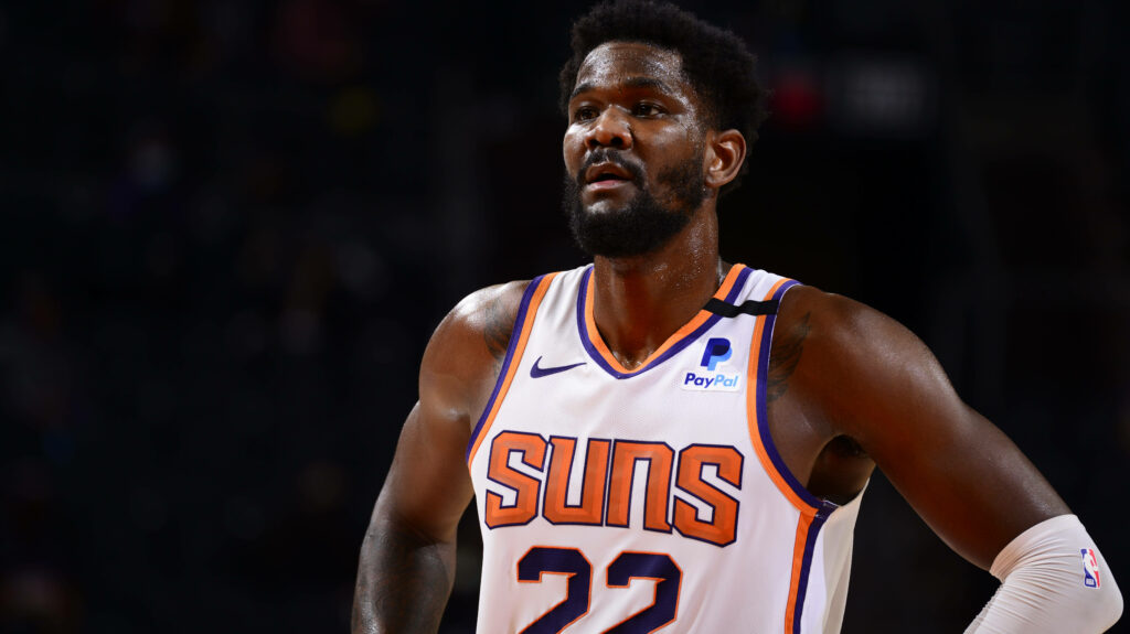 Deandre Ayton Phoenix Suns in white jersey performing intense basketball play with dramatic lighting Wallpaper