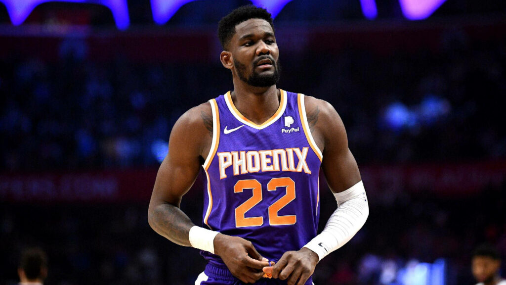 Deandre Ayton in Phoenix Suns uniform focused on court with bold lighting and vibrant colors Wallpaper