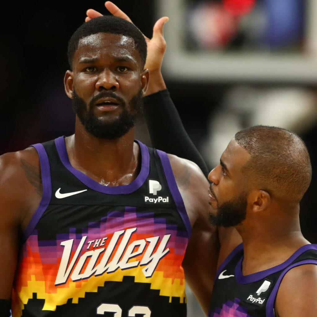 Deandre Ayton and Chris Paul in Phoenix Suns The Valley jerseys showing teamwork on court wallpaper