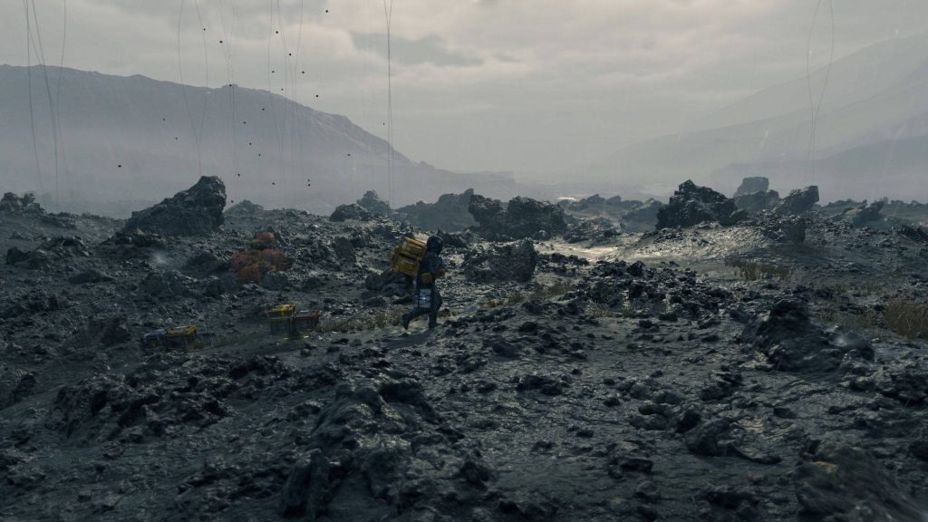 Sam Porter Bridges crosses rocky volcanic terrain under gray sky in Death Stranding wallpaper