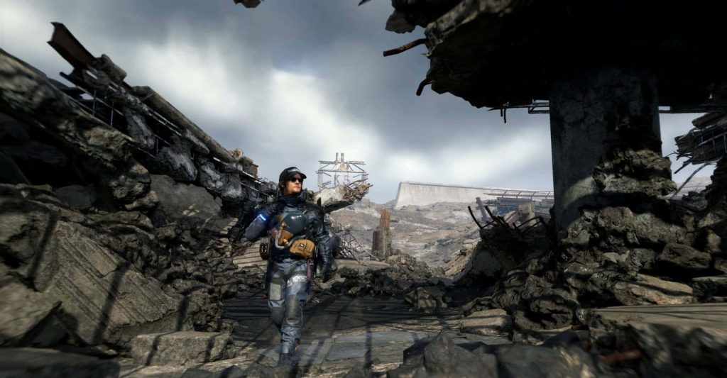 Sam Porter Bridges in iconic gear walks a desolate overcast post-apocalyptic Death Stranding landscape Wallpaper