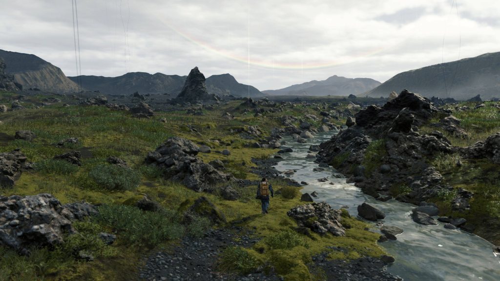 Sam Porter Bridges trekking mossy rocky terrain by stream under overcast sky Death Stranding wallpaper