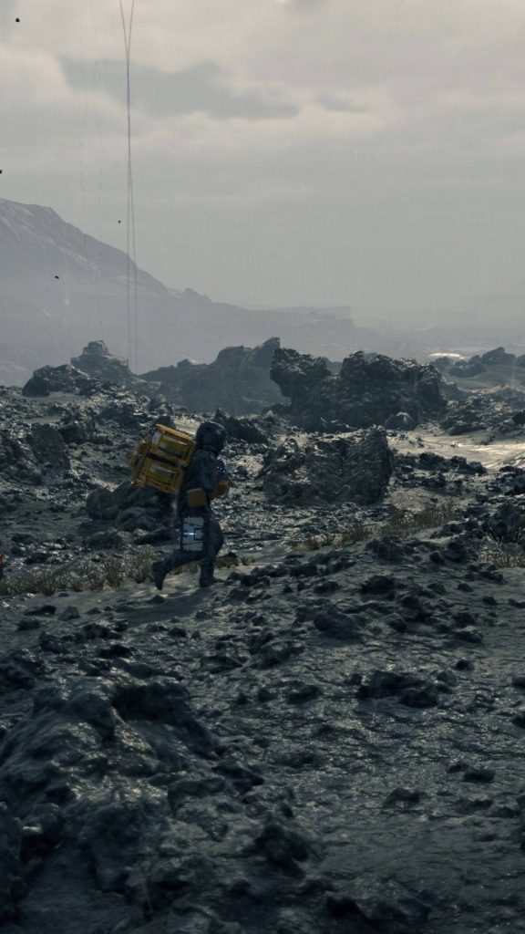 Sam Porter Bridges walking across rocky landscape under overcast sky Death Stranding wallpaper