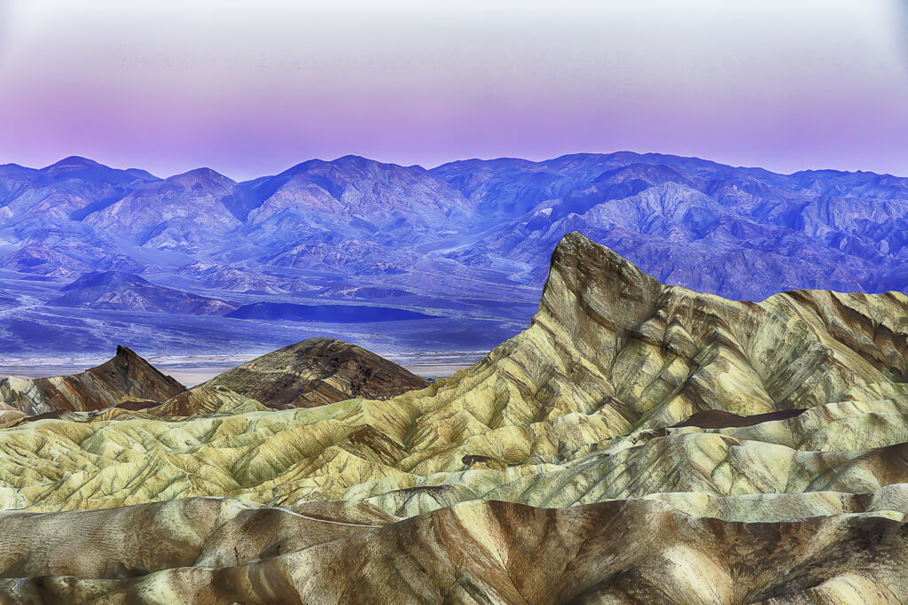 Sunset over Death Valley desert with rugged mountains and colorful rock formations wallpaper
