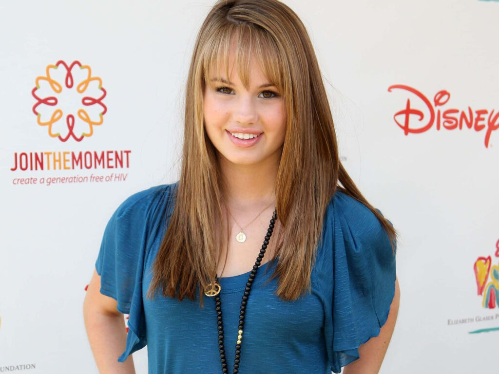 Debby Ryan smiling in teal blouse with colorful logo backdrop high-resolution celebrity wallpaper