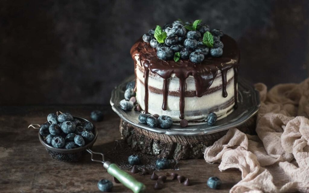 Decadent blueberry chocolate cake with creamy texture on rustic wooden background wallpaper