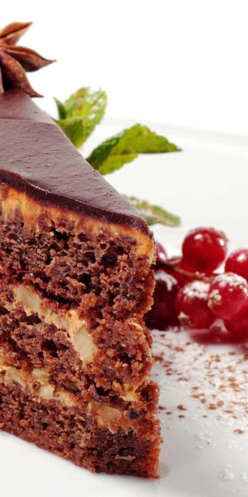 Close-up of rich chocolate cake slice with nuts cream red berries and mint dessert wallpaper