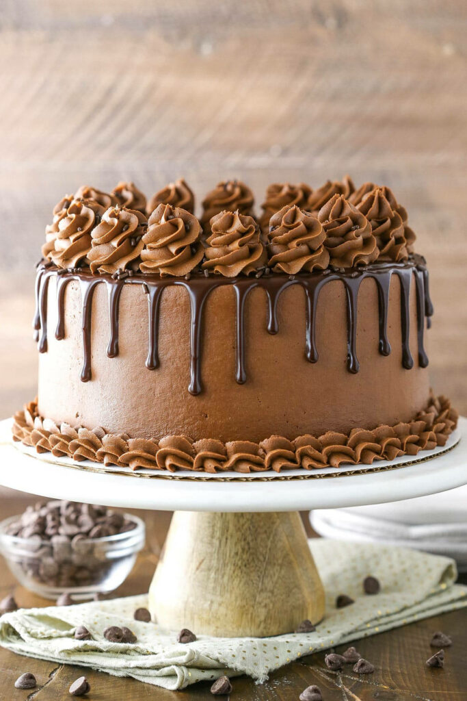 Chocolate cake with smooth icing rich ganache drips elegant swirls on rustic wooden background Wallpaper