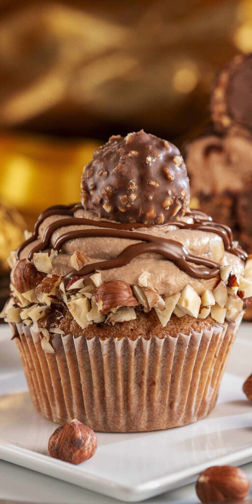 Decadent cupcake with chocolate frosting hazelnuts Ferrero Rocher on warm golden background wallpaper