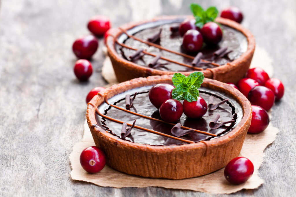 Delectable Chocolate Tarts Adorned with Berry Delights and Fresh Mint Leaf Wallpaper