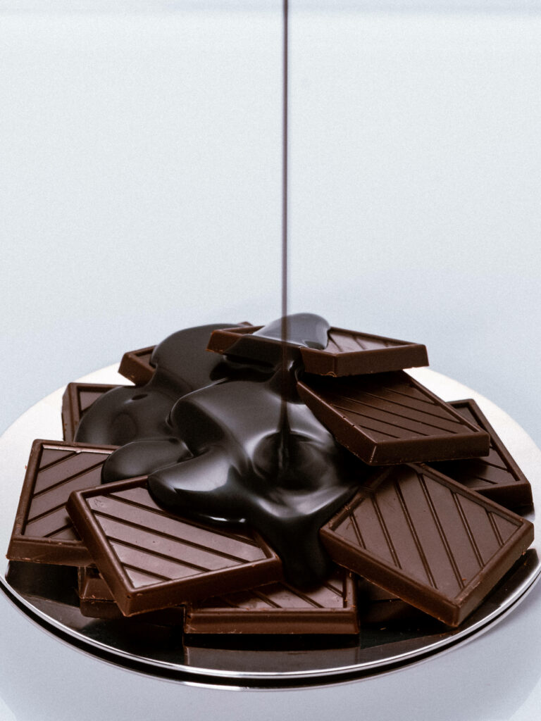 Dark chocolate syrup poured over glossy chocolate bars rich textures minimalist high resolution Wallpaper