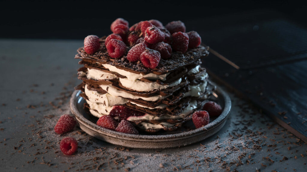 Decadent Chocolate Cake Blissfully Adorned with Cream and Raspberries Wallpaper