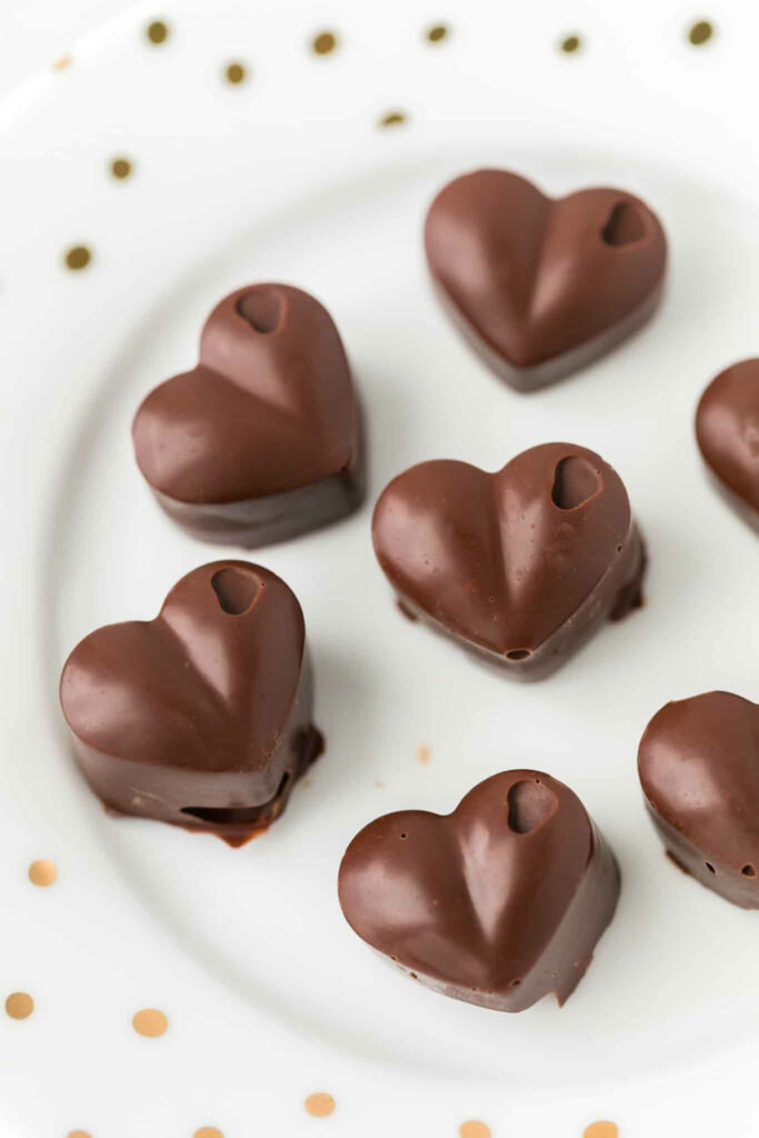 Decadent Brown Heart Chocolates on a White Plate: A Tempting Delight for Chocolate Lovers Wallpaper
