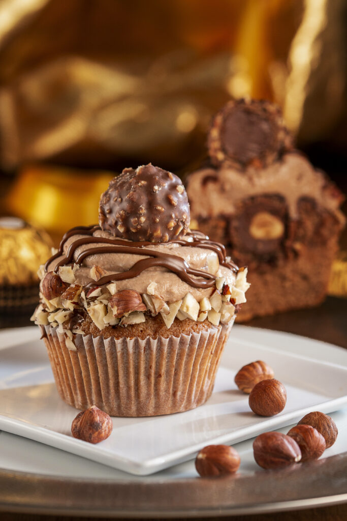 Ferrero Rocher cupcake with creamy chocolate frosting chopped hazelnuts on white plate dessert Wallpaper