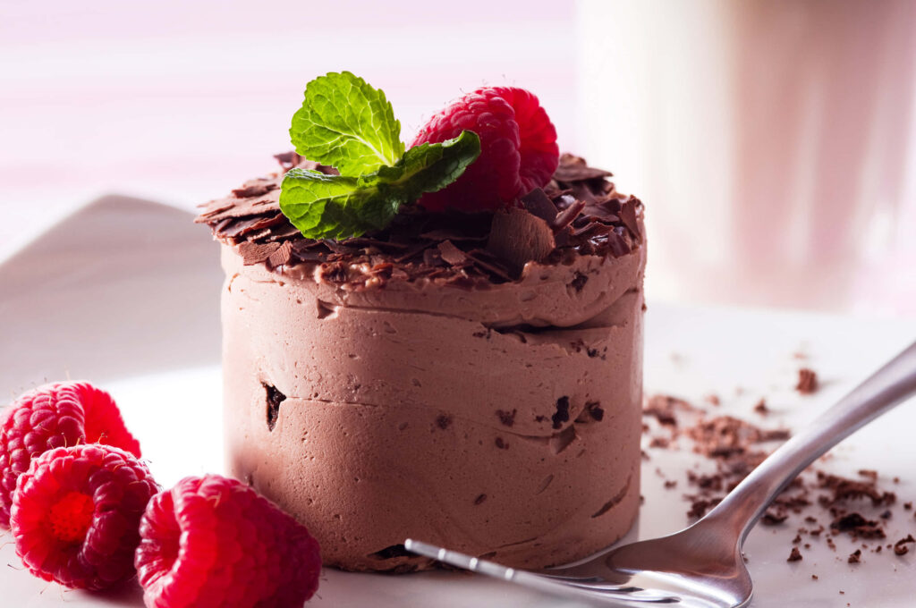 Chocolate Mousse Cake Adorned with Fresh Raspberries and Delicate Leaves Wallpaper