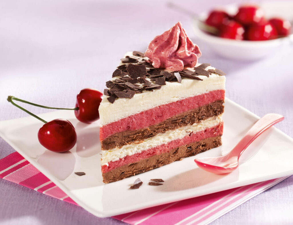 Vibrant layered cake wallpaper with chocolate shavings cherries and red cream swirl dessert background
