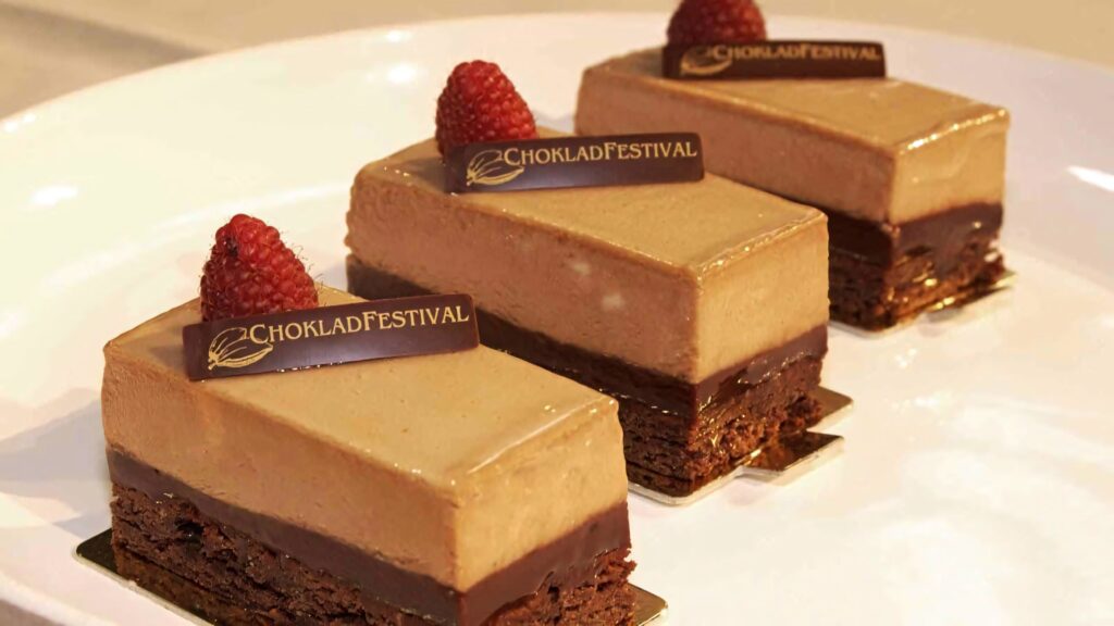 Three layered chocolate mousse cakes with ganache and raspberries on white plate dessert Wallpaper