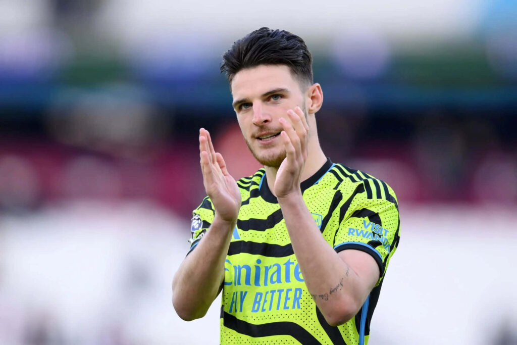 Declan Rice applauding on field in neon green and black kit with blurred background wallpaper