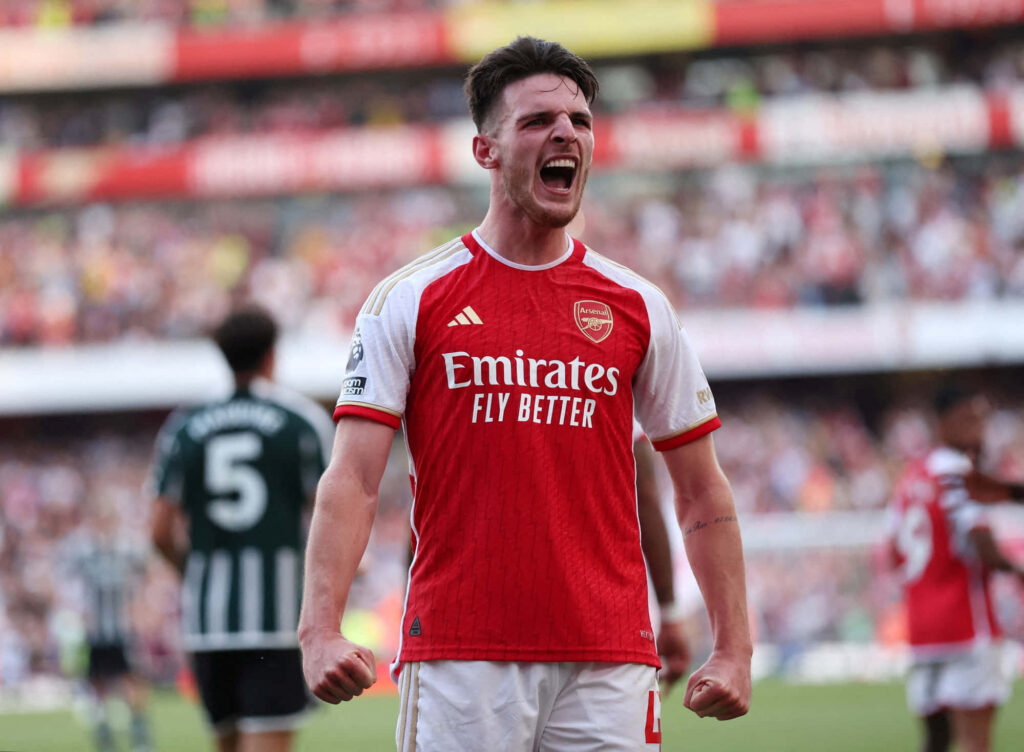 Declan Rice celebrating in red and white Arsenal kit with vibrant stadium background energy Wallpaper