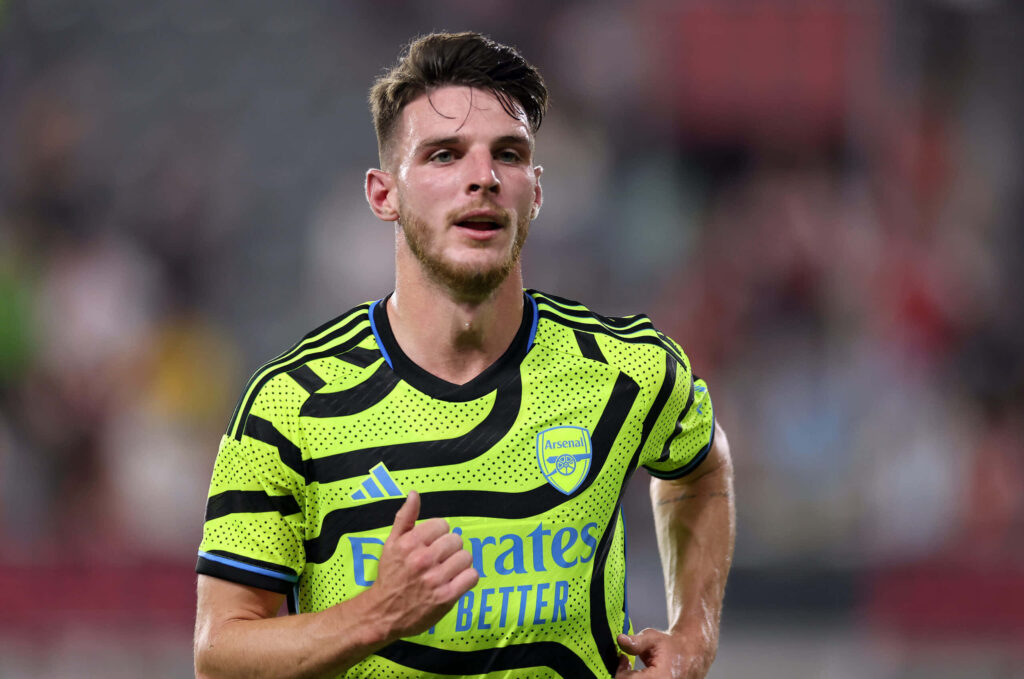 Declan Rice in Arsenal neon green away kit mid-action intense soccer match dynamic wallpaper