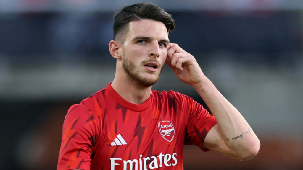 Declan Rice in Arsenal red kit with focused expression blurred stadium vibrant soccer wallpaper