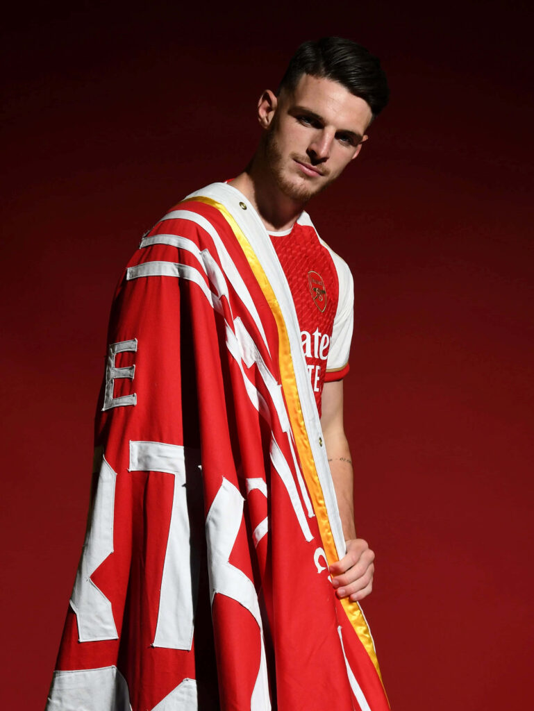 Declan Rice in Arsenal jersey with red and white flag on vibrant red background sports portrait wallpaper