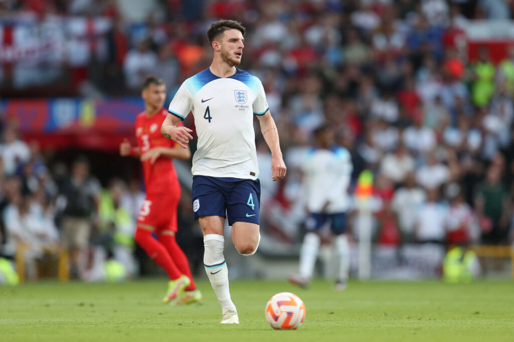 Declan Rice in England kit showing focus and skill on pitch with vibrant crowd and stadium background Wallpaper