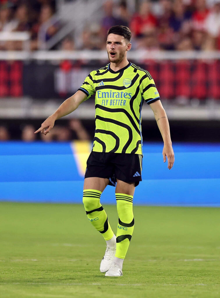 Declan Rice in neon soccer kit with bold black patterns on field dynamic athletic wallpaper background