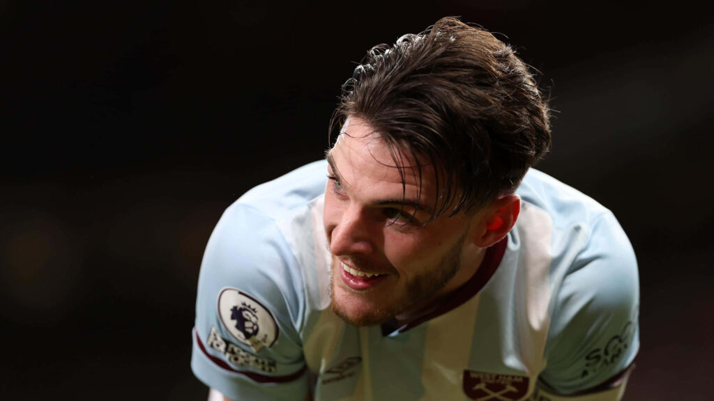 Declan Rice in West Ham kit smiling brightly with warm lighting dynamic footballer wallpaper
