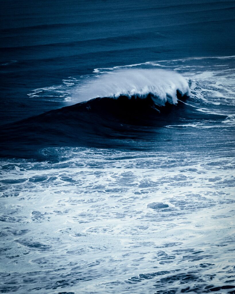 Deep blue ocean wave curling above frothy sea water wallpaper capturing surf energy and beauty