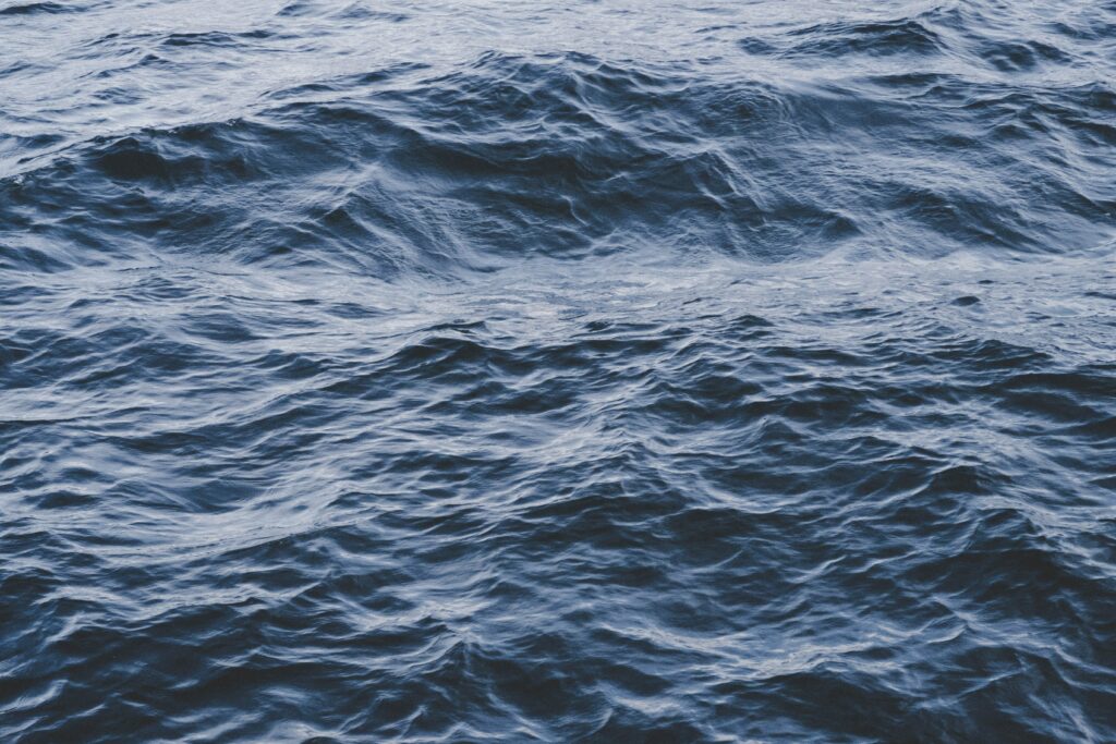 Deep blue ocean waves with intricate water textures and light reflections wallpaper background