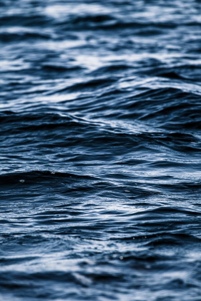 Close-up of deep blue ocean waves with gentle ripples and natural light enhancing water texture Wallpaper
