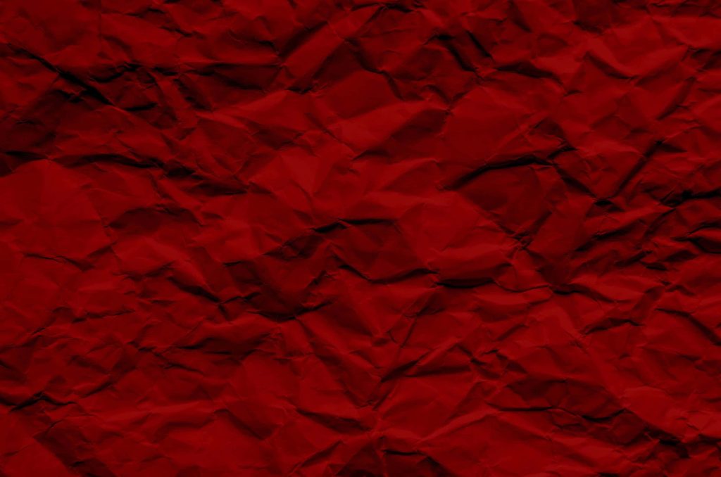 Deep red crumpled paper wallpaper with rich crimson hues and textured light shadow effects