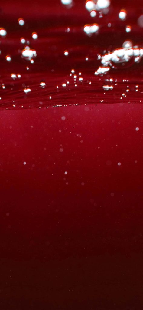 Close-up red liquid with shimmering bubbles and particles abstract iPhone wallpaper background