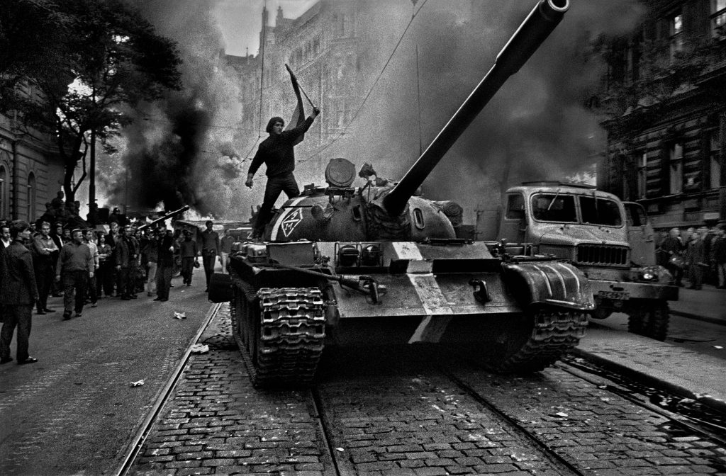 Defiant protester waving flag atop tank during 1968 Prague invasion black and white photo Wallpaper