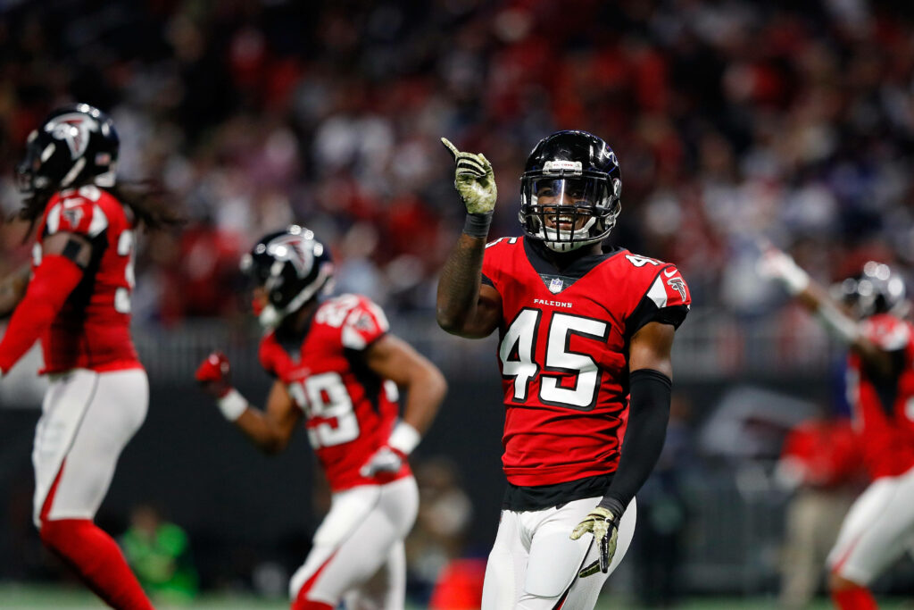 Atlanta Falcons linebacker Deion Jones celebrates with teammates in red and black uniform on field Wallpaper