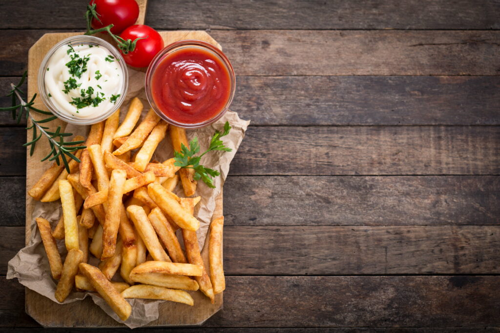 Crispy Delights: A Mouthwatering Still Life of Gourmet French Fries with Dipping Ketchup Wallpaper