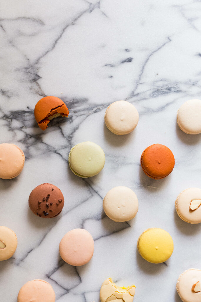 Sumptuous Assortment: Tempting Macarons and Tantalizing Citrus Bite on Elegant Marble Wallpaper