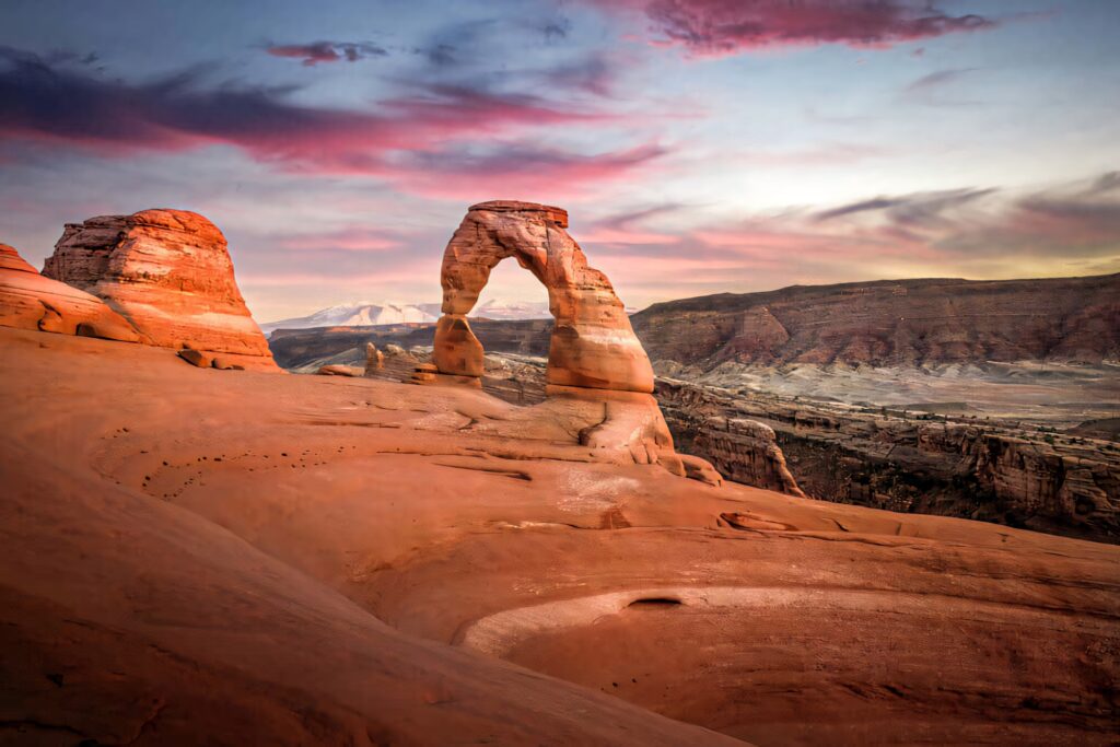 Delicate Arch at sunset with colorful sky and red rock formations Utah iconic landscape view Wallpaper